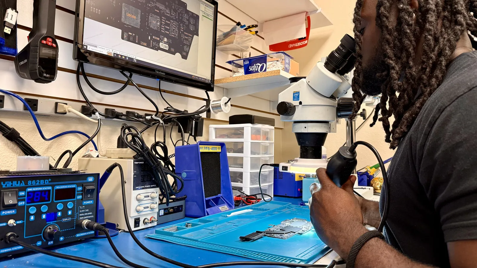 Microsoldering a circuit board under the microscope at the iGeek repair bench