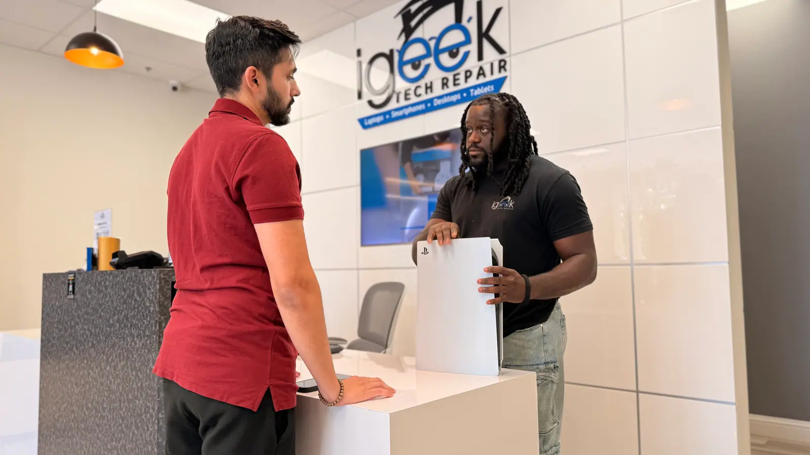 Technician handing a game console back to a customer at the counter
