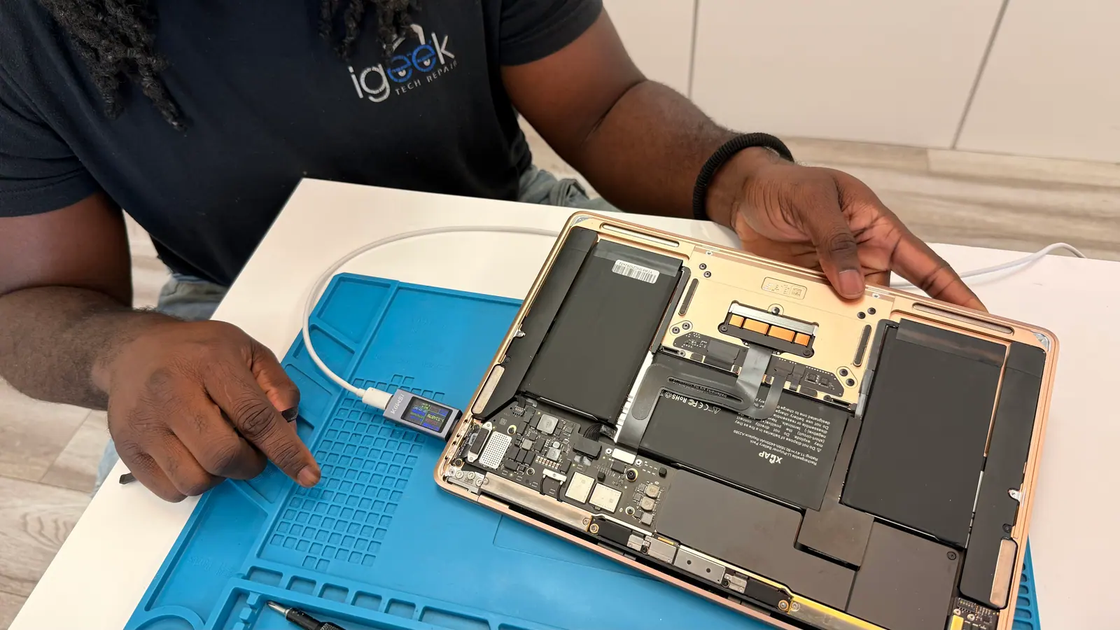 Opened MacBook showing the battery and logic board on the repair mat