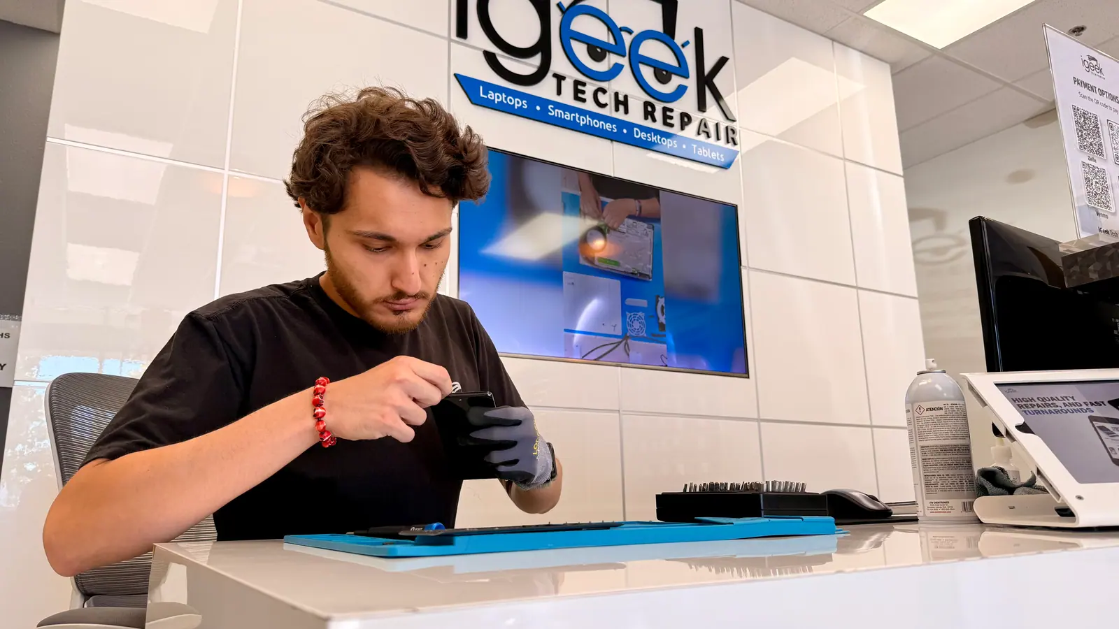 iGeek technician opening a smartphone on the repair mat at the front counter