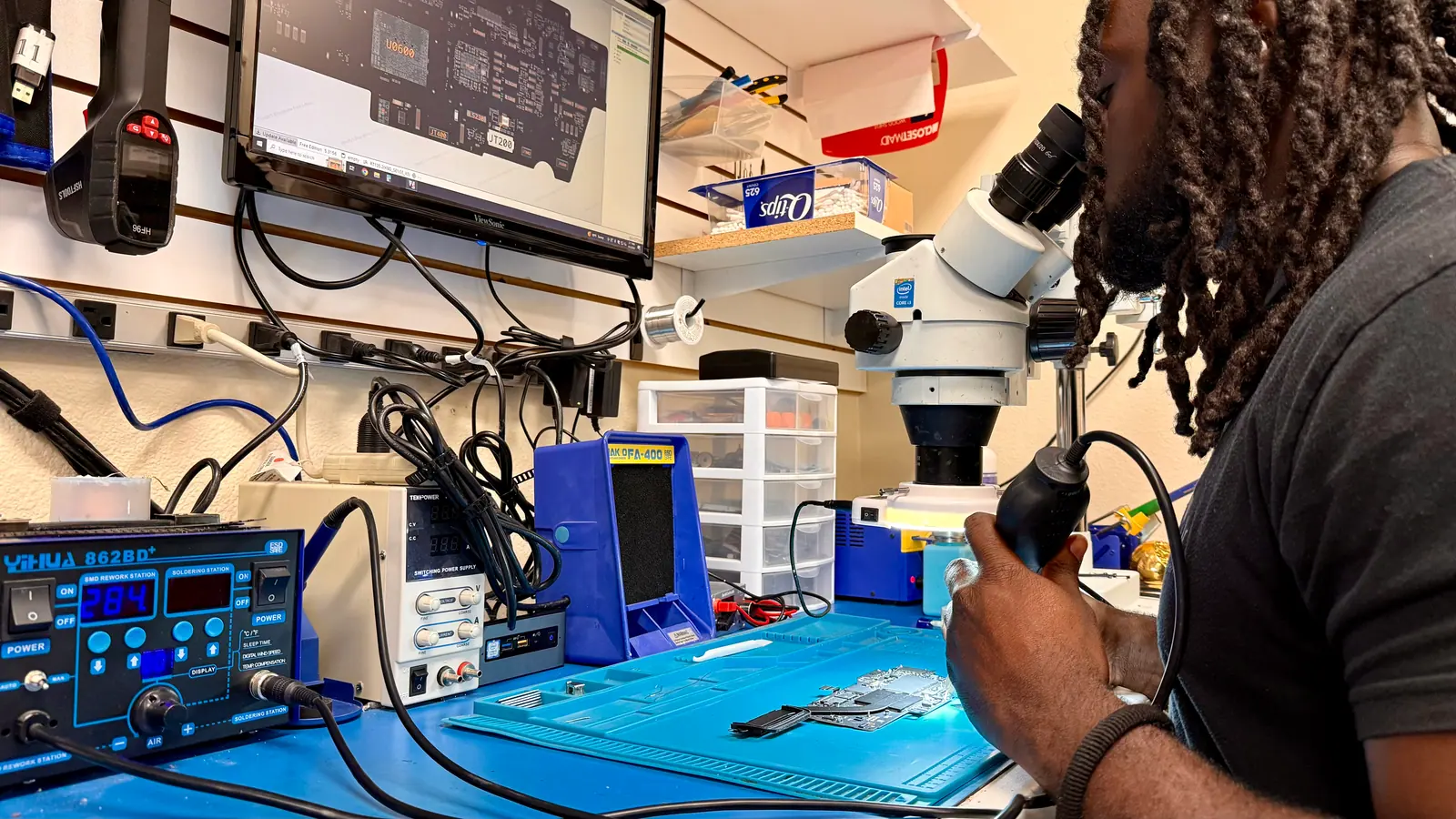iGeek technician looking through a stereo microscope at the board repair station